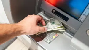 Mano che ritira contanti da uno sportello bancomat