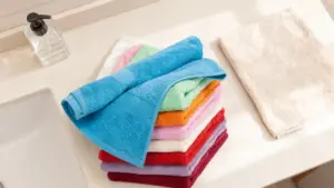 Asciugamani colorati piegati su una superficie del bagno accanto a un dispenser di sapone