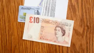 Banconota da dieci sterline accanto a una patente di guida su un tavolo in legno