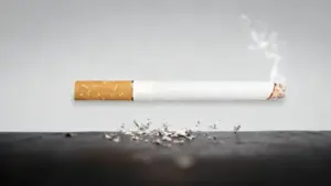 Sigaretta accesa con cenere su una superficie scura