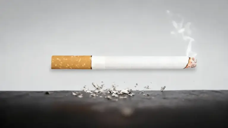 Sigaretta accesa con cenere su una superficie scura