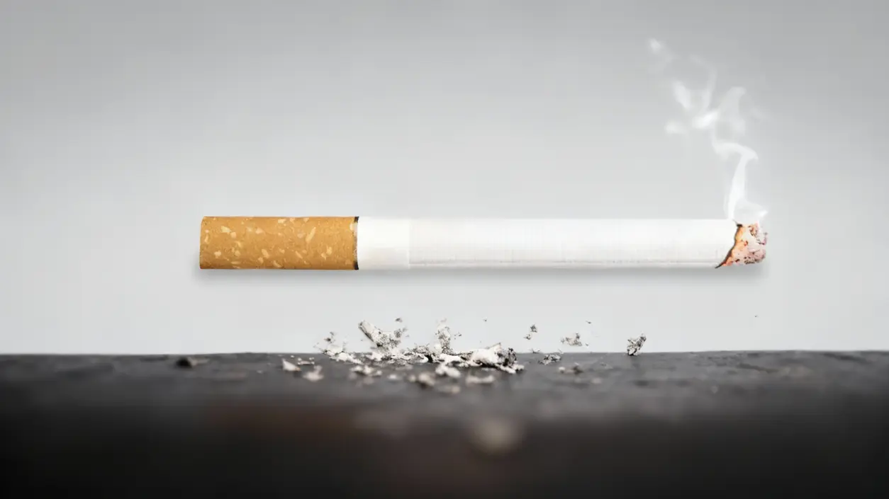 Sigaretta accesa con cenere su una superficie scura