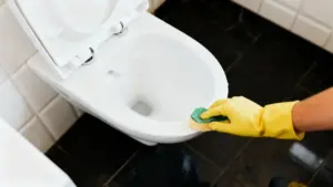 Persona con guanti pulisce il WC con una spugna in un bagno