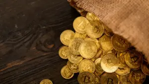Monete d'oro con simbolo Bitcoin sparse su un tavolo in legno scuro