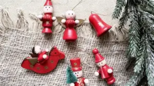 Addobbi natalizi artigianali in legno dipinti di rosso su tessuto grezzo