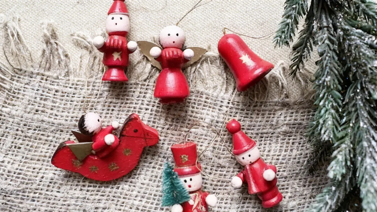 Addobbi natalizi artigianali in legno dipinti di rosso su tessuto grezzo